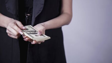 Close up business woman recounts US Dollar money. Earnings, profits, accounting concept.の写真素材