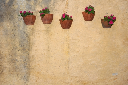 flowerpots with pink flowers hanging on a house wallの写真素材