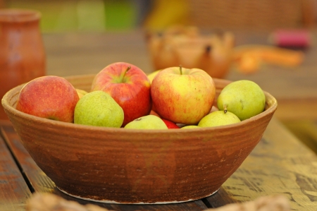 apples in a clay bowl on a wooden tableの写真素材
