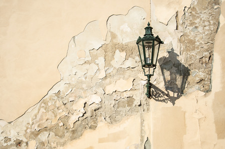 an ancient dark green squiggly lantern casting a cloud over a grungy house wall in Prag - Czech Republicの写真素材
