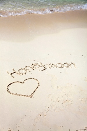 Honeymoon text and heartshape in sand on tropical beachの写真素材