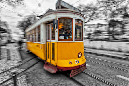 View of the traditional yellow Tram 28 passing through the streets of Lisbon, Portugal providing innercity public transportのeditorial素材