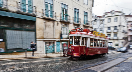 View of the traditional red Tram 28 passing through the streets of Lisbon, Portugal providing innercity public transportのeditorial素材