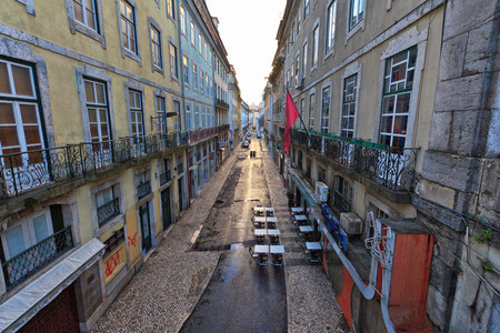 Street scene in Lisbon city centre with a deserted street running between multistorey historical buildings with decorative balconies and shops at ground levelのeditorial素材
