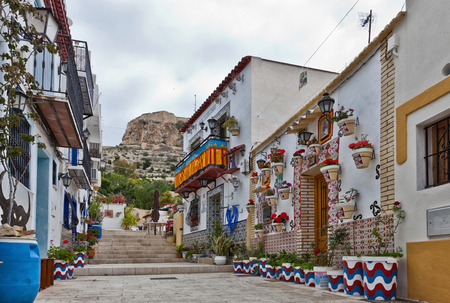 Colourful street in Alicante, Spain with buildings adorned with murals, potted plants, balconies and traditional Spanish tilesのeditorial素材
