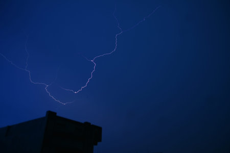 Dramatic nighttime view of a lightning bolt streaking across the dark blue sky.