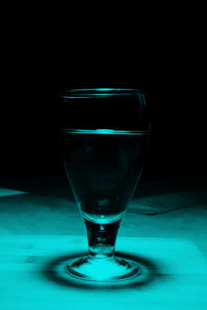 wine glass with wine on wooden table. Top angle lighting shadow comes on the table.の写真素材