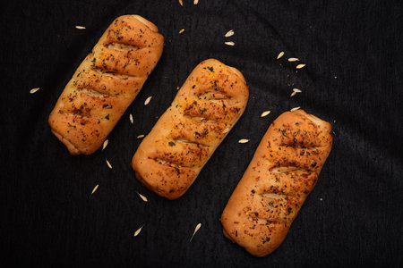 Bread roll and bunch of wheat on black background. food background concept.の写真素材