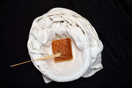 one bread piece and wheat in white cloth basket on black background.の写真素材