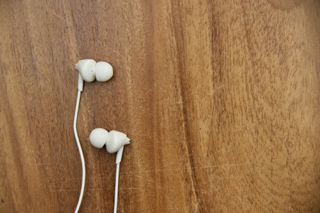 White wired earphone with wooden background with text space .