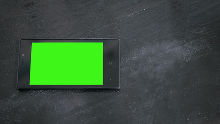 Smart phone with green screen on black wooden table backgroundの写真素材