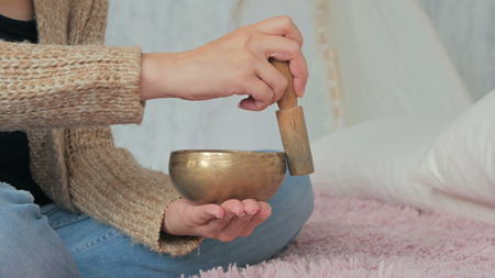 Young woman in cardigan relaxing with nepal singing bowl. Meditation and relax concept.の写真素材