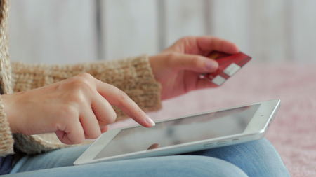 Young woman buying goods from the internet and entering number security code from credit card on digital tablet. Online, technology and internet conceptの写真素材