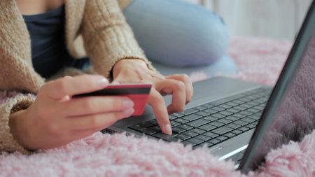 Close up shot. Young woman buying goods from the internet and entering number security code from...