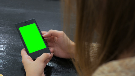 Woman looking at smartphone with green screen. Close up shot of woman's hands with mobileの写真素材