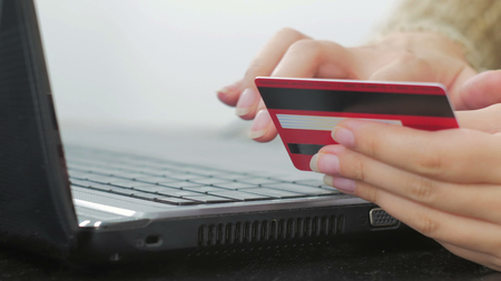 Close up shot. Young woman buying goods from the internet and entering number security code from credit card on laptop. Online, technology and internet concept.の写真素材