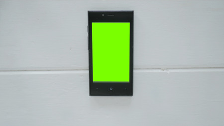 Smartphone with green screen on white wooden backgroundの写真素材
