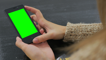 Woman using vertical smartphone with green screen. Close up shot of woman's hands with mobile Close up shot of woman's hands with mobileの写真素材
