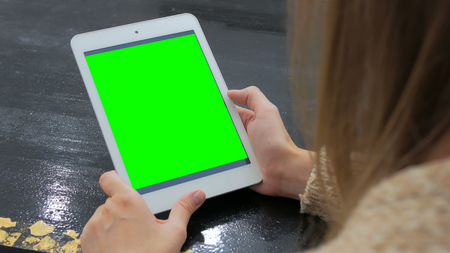 Woman looking at vertical tablet computer with green screen. Close up shot of woman's hands with padの写真素材