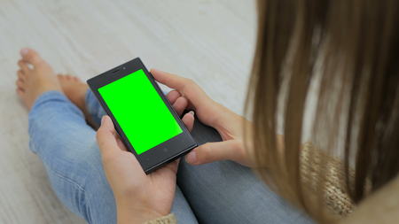 Woman looking at smartphone with green screen. Close up shot of woman's hands with mobileの写真素材