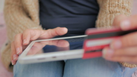 Young woman buying goods from the internet and entering number security code from credit card on digital tablet. Online, technology and internet conceptの写真素材