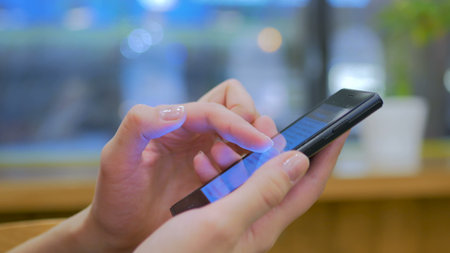 Close-up shot of woman hands with smartphone in cafe. Technology conceptの写真素材
