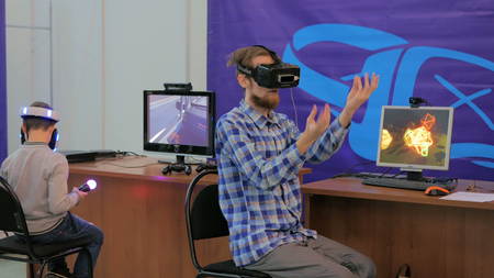 NIZHNIY NOVGOROD, RUSSIA - JANUARY 28, 2017: Exhibition of modern technologies. Virtual reality game. Young man using virtual reality glasses. VRのeditorial素材