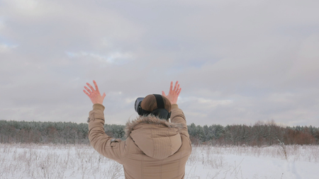 Woman putting on and using virtual reality glasses in winter forest. Virtual reality mask. VR. Future, nature, winter and technology conceptの写真素材