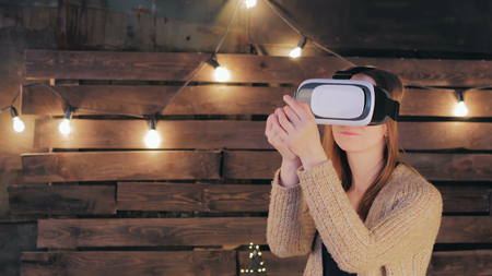 Young woman using Virtual Reality Glasses. Virtual reality mask. VR. Retro loft Christmas background with light bulbsの写真素材