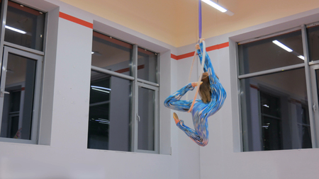 Plastic beautiful girl gymnast on acrobatic circus ring in blue suit. Aerial ring. Acrobatic and sport conceptの写真素材