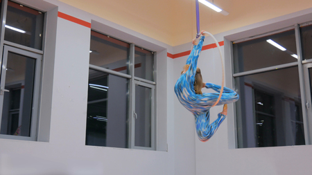 Plastic beautiful girl gymnast on acrobatic circus ring in blue suit. Aerial ring. Acrobatic and sport conceptの写真素材