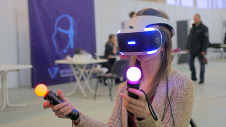 Virtual reality game. Young woman using virtual reality glasses and hand controlers
