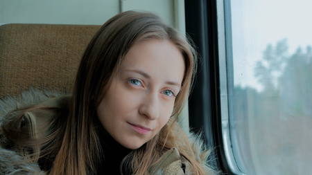 Close up shot of pensive woman relaxing and looking out of a train window. Travel, transport and winter conceptの写真素材