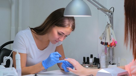 Manicurist master makes manicure on young woman handの写真素材
