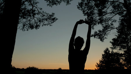Happy woman stretching in the forest after sunset. Freedom and happiness conceptの写真素材