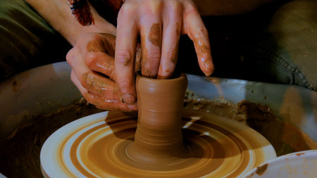 Professional male potter working with clay on potters wheel in workshop, studio. Handmade, art and...