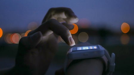 Young woman using wearable smartwatch computer device in the city. Evening time, twilight. Relax, entertainment and technology conceptの写真素材