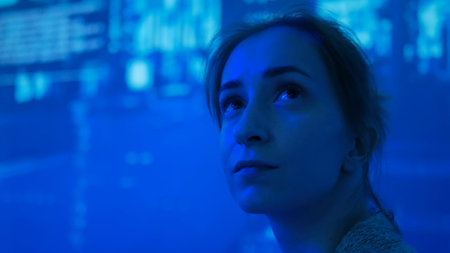 Woman looking around and watching video presentation on large display wall at futuristic technology exhibitionの写真素材