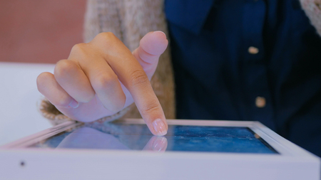 Woman using interactive touchscreen display at urban exhibition - scrolling and touching. Entertainment and technology conceptの写真素材