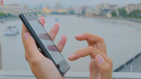 Woman using smartphone on embankment - close up shot - scrolling and touching. Technology conceptの写真素材