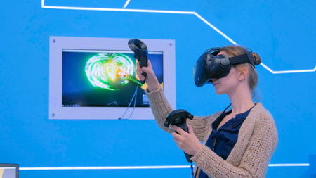 Young woman using virtual reality headset and drawing with special joystick at technology...