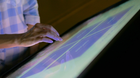 Woman using interactive touchscreen display at modern museum. Education and technology conceptの写真素材