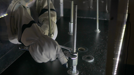 Interactive exposition in science museum - simulation of repair work in space at technology museum. Close up shot of woman hands in astronaut gloves with special repair tools. Astronautics conceptの写真素材