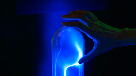 Interactive exposition in science museum. Woman touching plasma glass flask. Electricity and physics conceptの写真素材