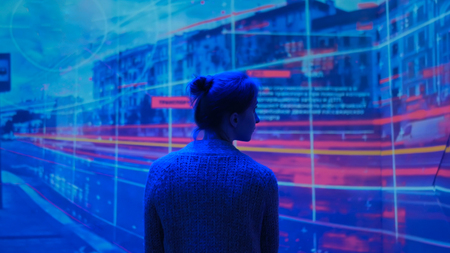 Woman looking around and watching video presentation on large display wall at futuristic technology exhibitionの写真素材