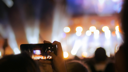 Unrecognizable hands silhouette taking photo or recording video of live music concert with smartphone at night. Photography, entertainment and technology conceptの写真素材
