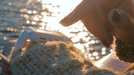 Woman using wearable smartwatch computer device on deck of cruise ship at sunset. Sunset light, golden hour. Technology and journey conceptの写真素材