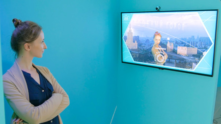 MOSCOW, RUSSIA - July 30, 2018: Smart City Exhibition. Woman taking selfie photo in front of interactive display. Leap motion and future conceptのeditorial素材