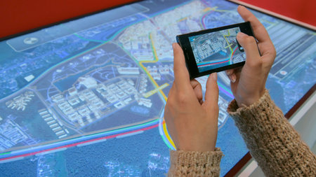 Woman hands taking photo of interactive exhibit with smartphone at urban exhibition. Photography and...