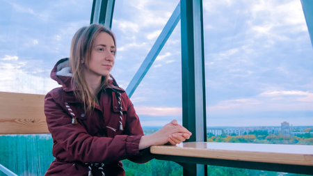 Woman looks at the park from cabin of Ferris wheel. Leisure time, travel and entertainment concept